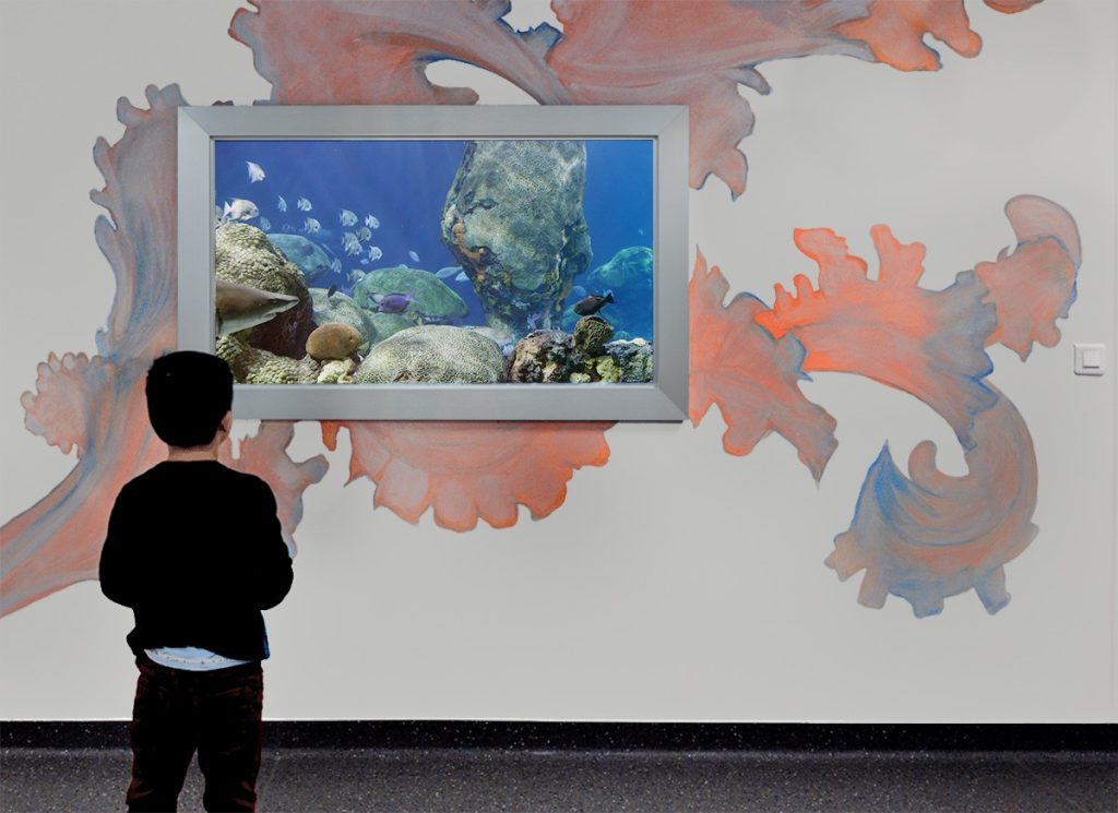 Child at the Armaned Trousseau Hospital watching reef fish swim in Sky Factory's eSea Digital Virtual Aquarium Photo Credit Raphael Vialle