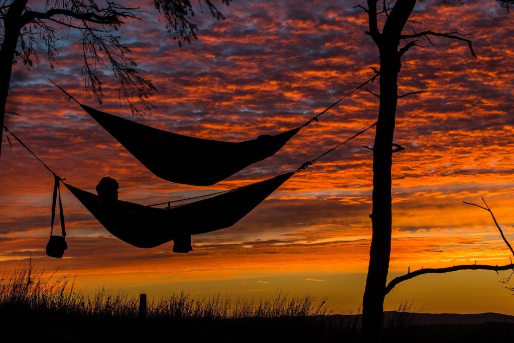 Couple relaxing in hammocks at sunset