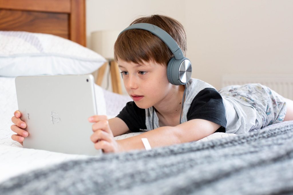 Child on Bed Watching Tablet with Headphones 1
